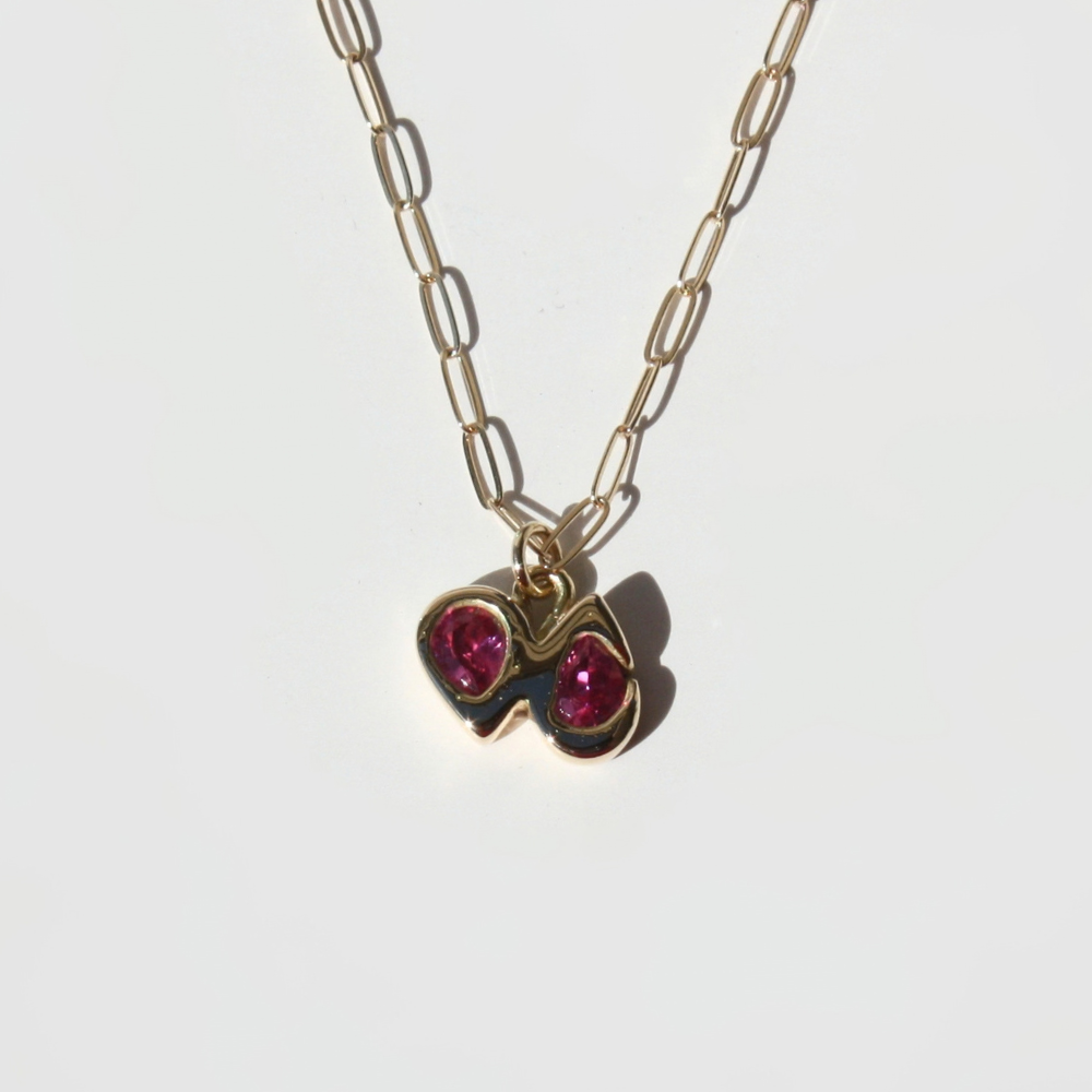 "Detail view of organic sand cast 14k gold texture with two cast in place fuchsia pear gemstones."