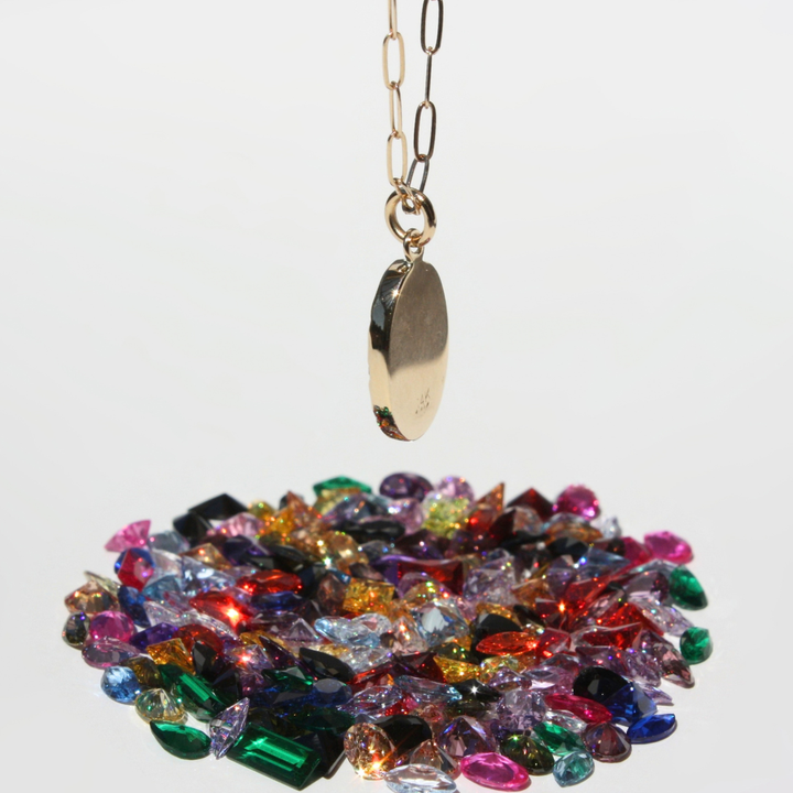 "Detail view of organic sand cast 14k gold coin texture with cast in place lab grown fireable rainbow gemstones."