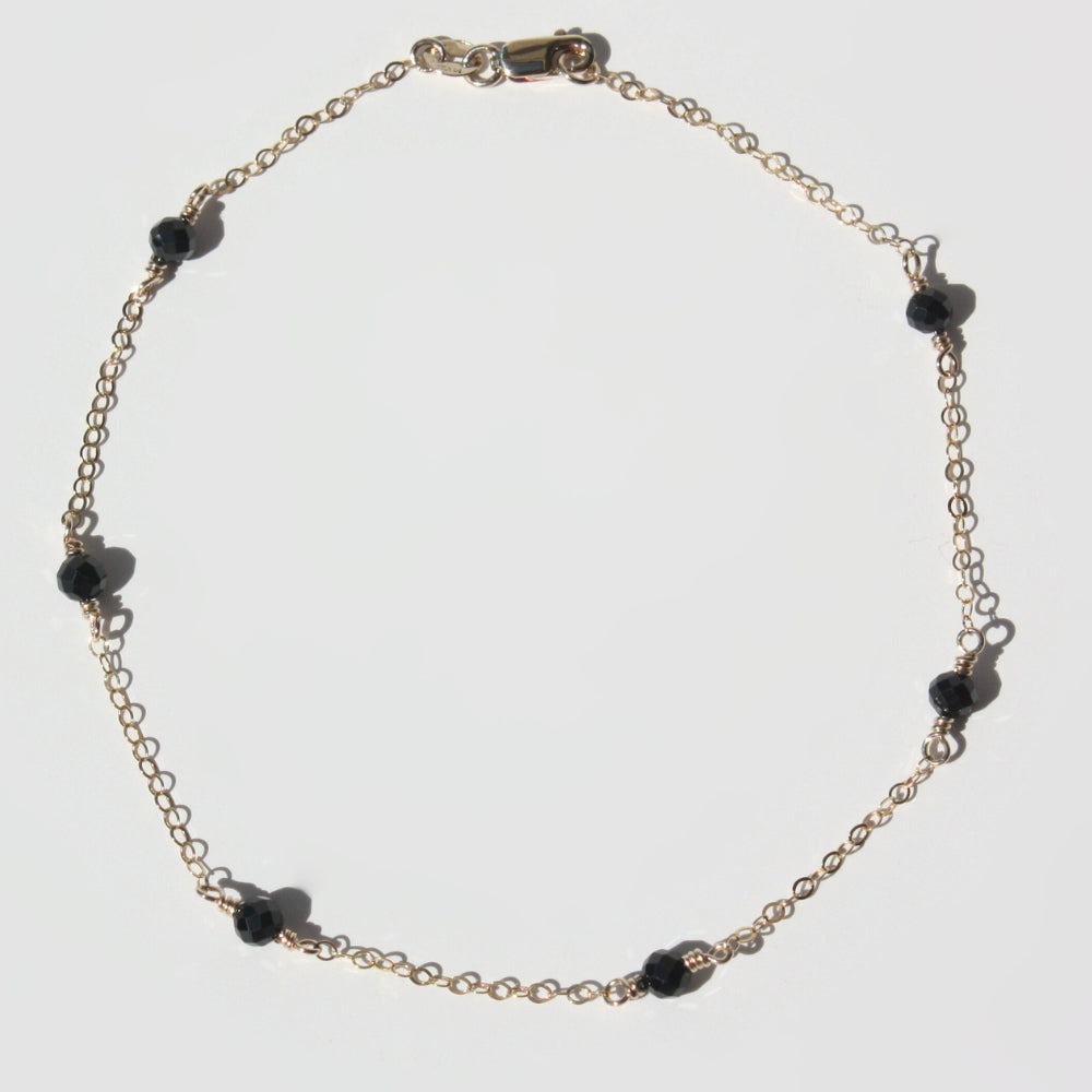 Handmade 14K gold filled gemstone station anklet on a clean display showing floating colorful gemstones.