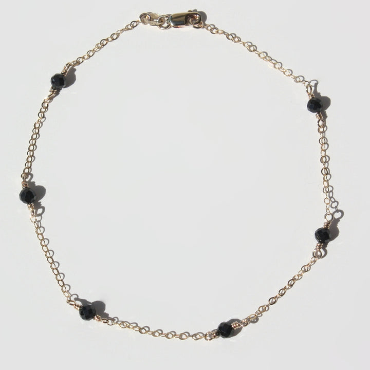 Handmade 14K gold filled gemstone station anklet on a clean display showing floating colorful gemstones.