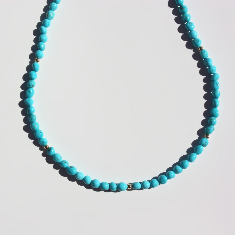 Close up of Joyful and Co Sleeping Beauty turquoise pebble necklace hand knotted in silk with 14K gold clasp