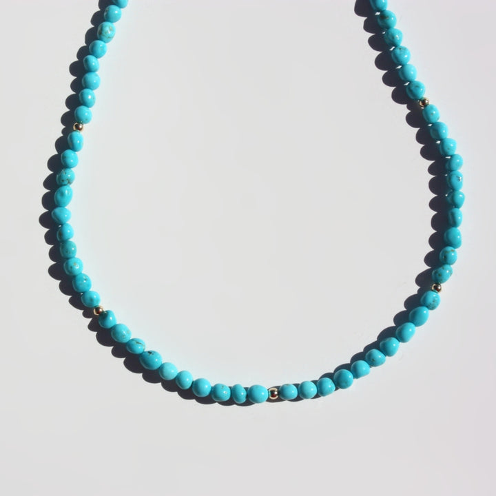 Close up of Joyful and Co Sleeping Beauty turquoise pebble necklace hand knotted in silk with 14K gold clasp