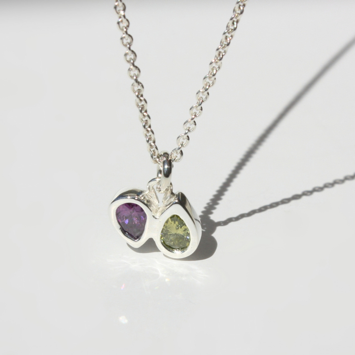 "Detail view of organic sand cast fine silver texture with two cast in place pear cut gemstones."