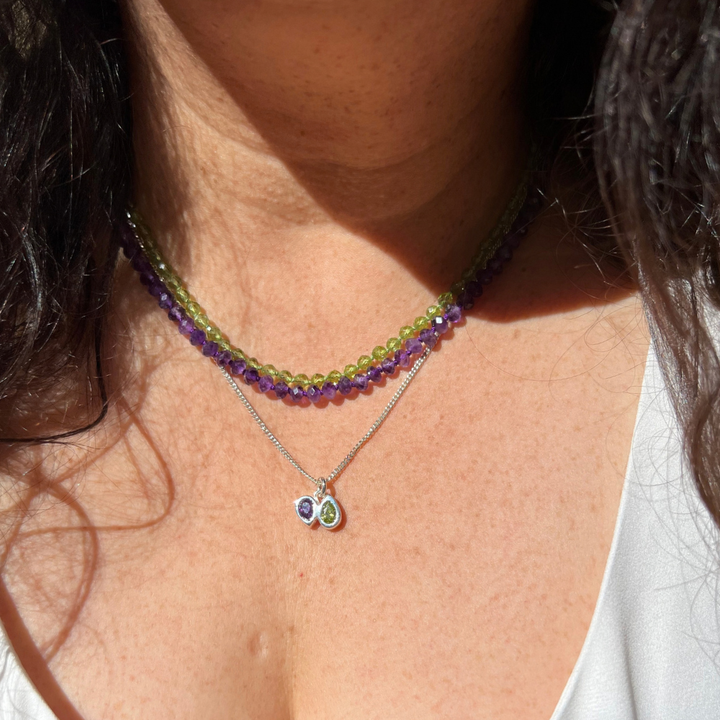 Model wearing two layered beaded necklace and fine silver double pear cut gemstone pendant necklaces with multiple birthstone colors combinations.