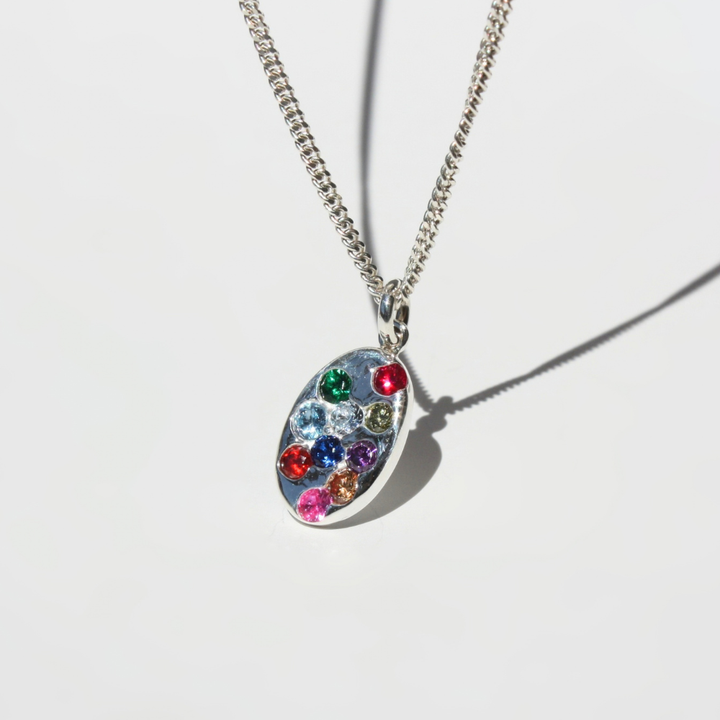 "Detail view of organic sand cast fine silver coin texture with cast in place lab grown fireable rainbow gemstones."