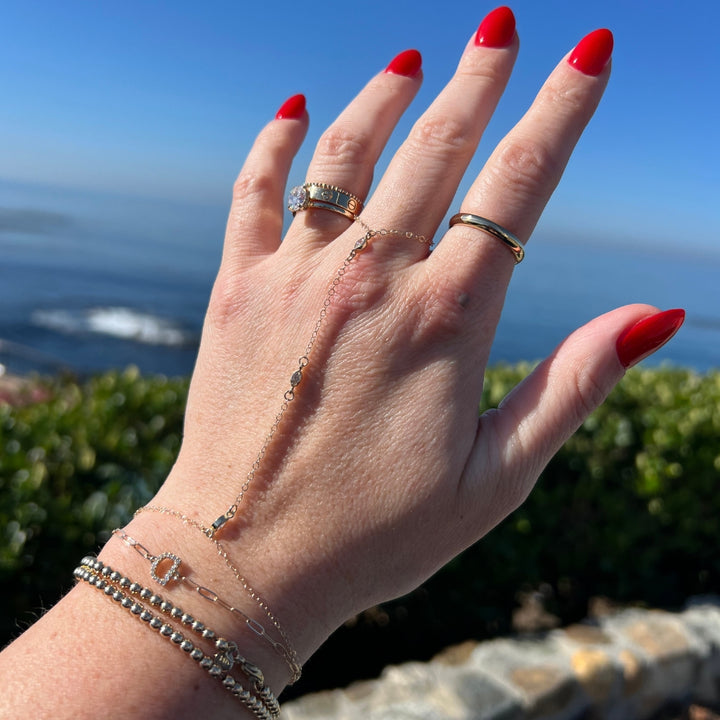 Model wearing a 14k gold marquise diamond hand chain connecting from wrist to finger.