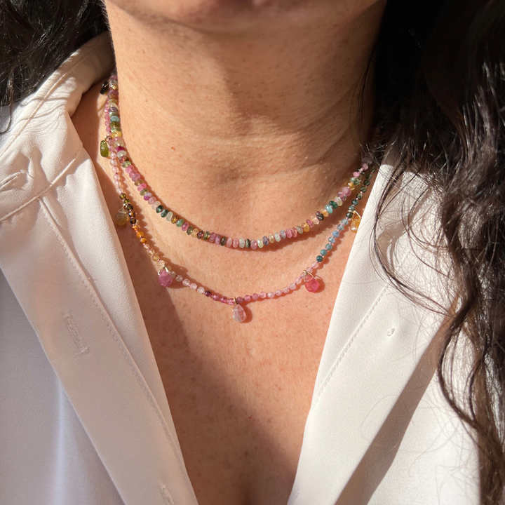 "Model wearing a hand-knotted silk watermelon tourmaline beaded teardrop necklace layered with gold chains."
