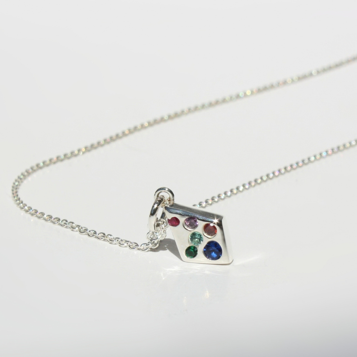 "Detail view of organic sand cast fine silver kite texture with cast in place lab grown multi-color gemston