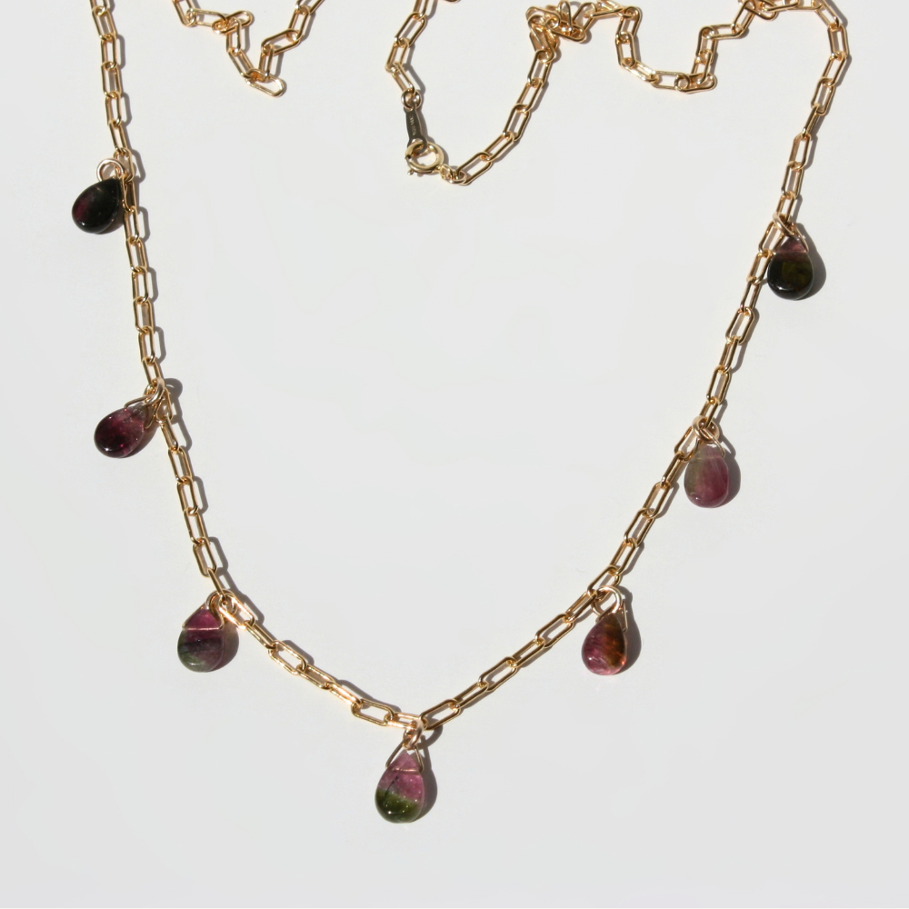 "Joyful and Co watermelon tourmaline teardrop paperclip necklace in gold showing scattered pink and green gemstones."