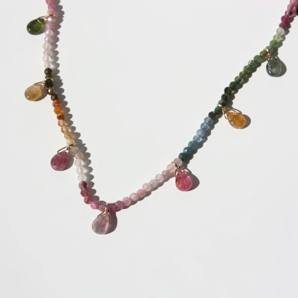 "Detail view of silk hand-knotting between watermelon tourmaline beads and faceted teardrop drops."