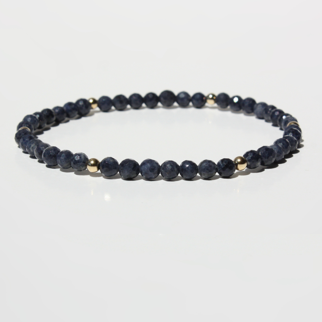 Navy blue beaded bracelet with gold accents on a white background