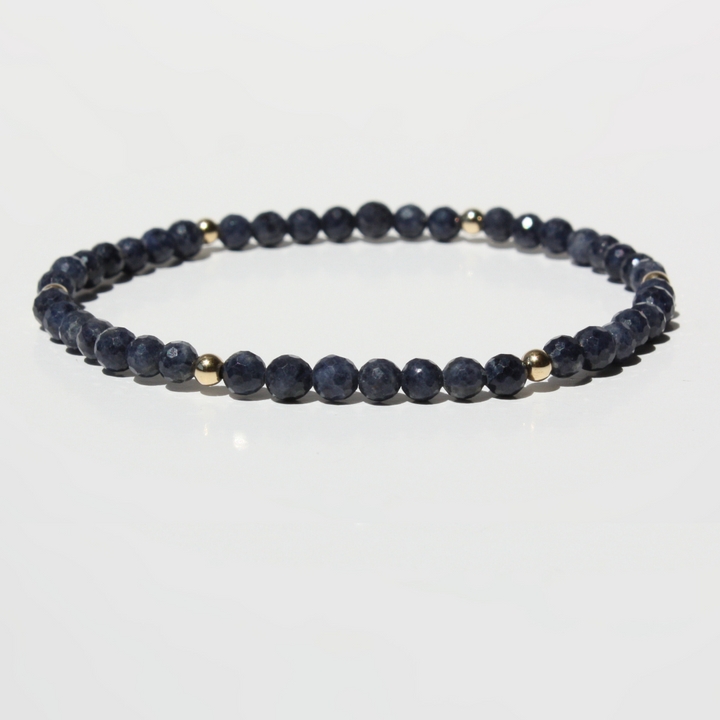 Navy blue beaded bracelet with gold accents on a white background